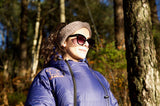 dame med pannebånd og solbriller i skogen ikledd en utekos jakke i dun