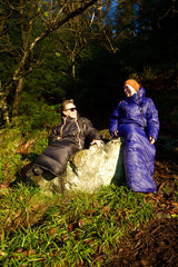 to kvinner ikledd hver sin Utekos dress sittende i naturen på en stein