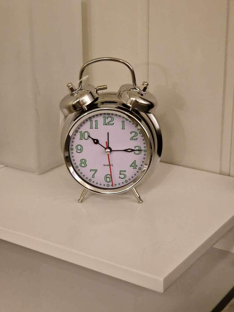 Klassisk vekkeklokke i sølv plassert på et nattbord