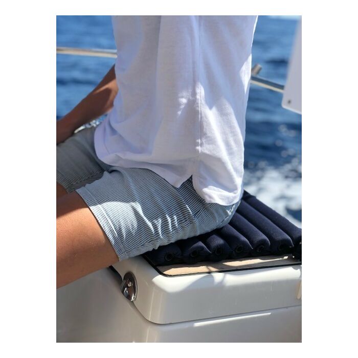 person med blåstripete shorts sittende i en båt på en fenderpute